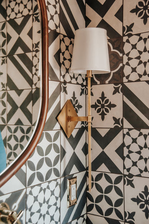 Cortland Wall Sconce in aged brass shown from the front to reveal the arm curve and shade silhouette.
