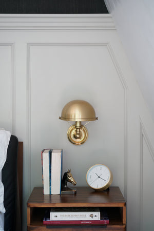Close-up of the Covington Wall Sconce in aged brass showing the arm curve and shade silhouette.