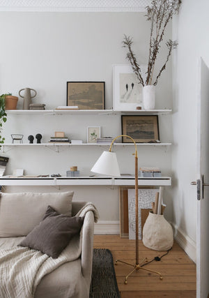 Curves No.1 Floor Lamp in aged brass styled in a reading nook for warm, layered light at Laurie Yapp Home.
