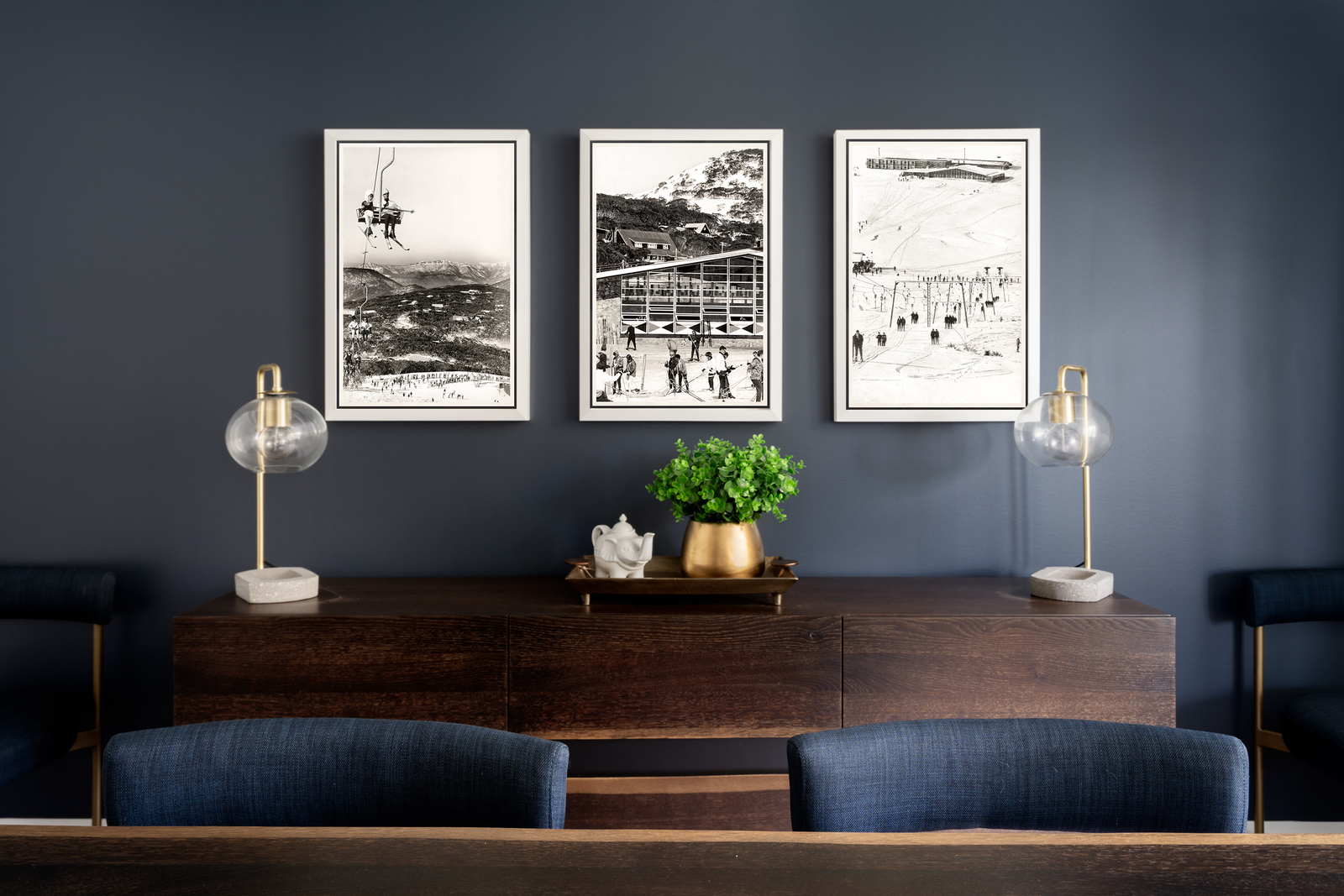 Navy dining room with a dark wood credenza and framed black-and-white mountain photography.