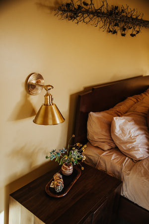 Close-up of the Garden City Wall Sconce 8" x 11" in aged brass showing the arm curve and shade silhouette.