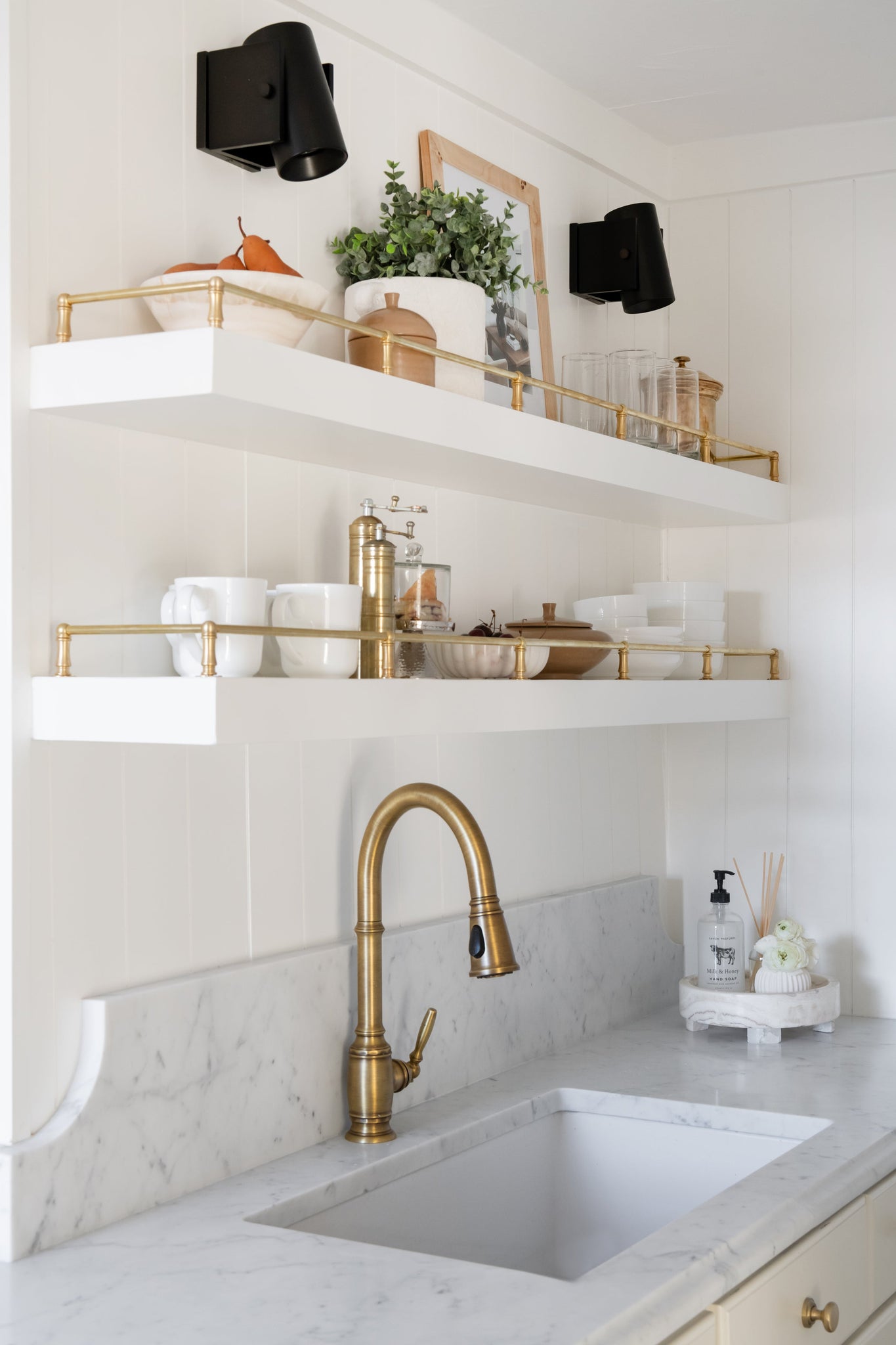 Nowra Wall Sconce in Aged Brass styled in a curated living room for warm, layered light at Laurie Yapp Home.