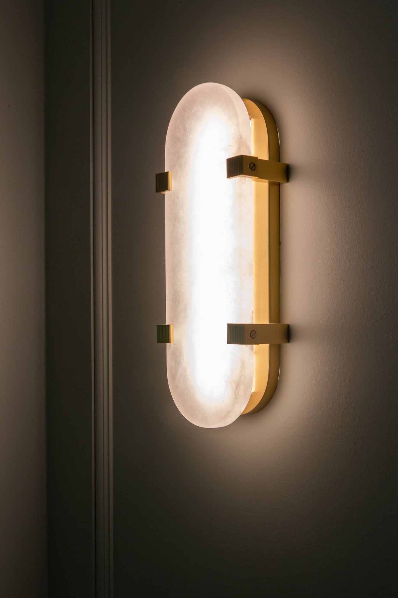Skylar Wall Sconce 5.75" x 13.75" in aged brass styled in a warmly lit hallway for warm, layered light at Laurie Yapp Home.