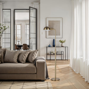 Cos floor lamp placed beside a sofa in a modern living room setting.