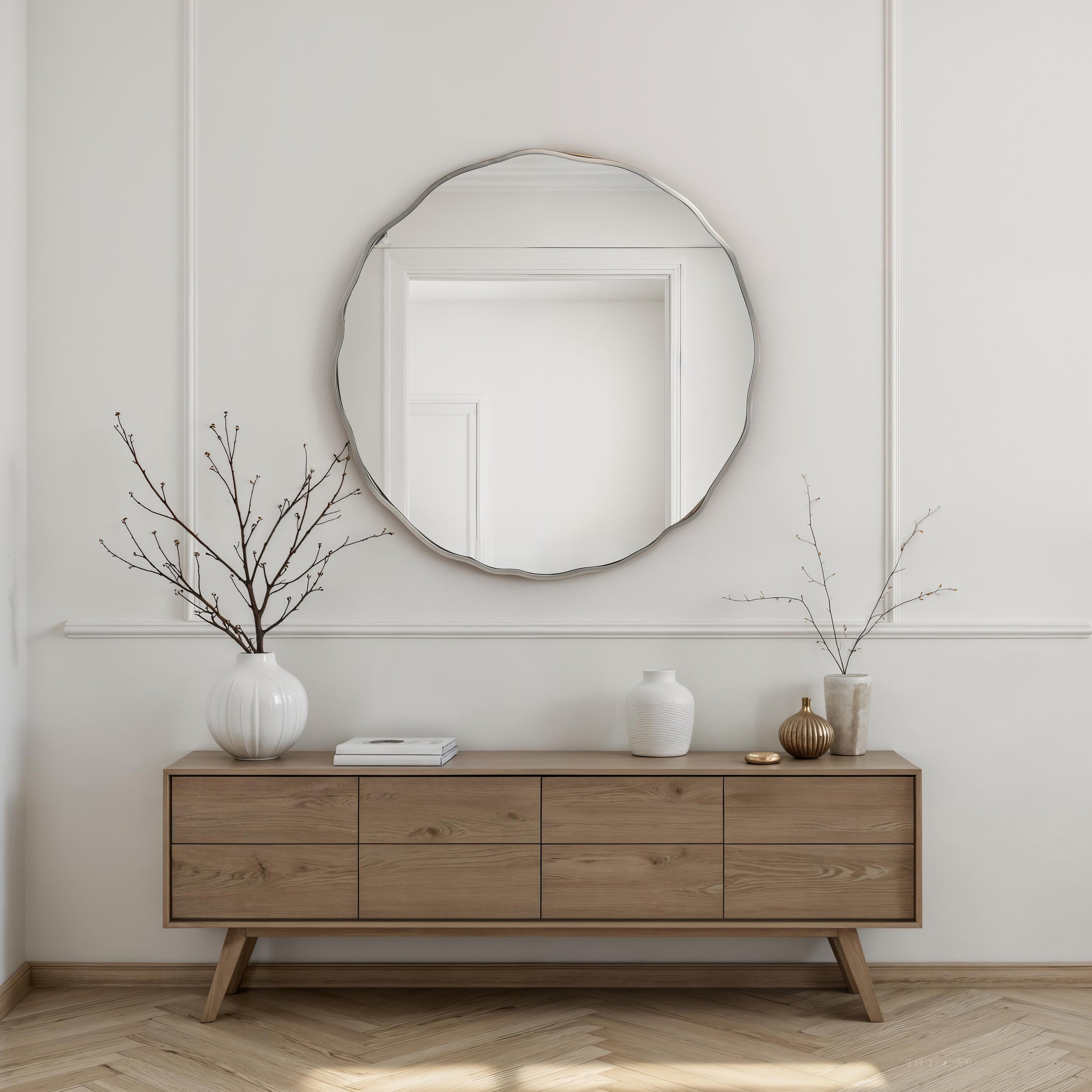 Knox mirror above a wooden sideboard, styled with vases and branches in a modern interior.