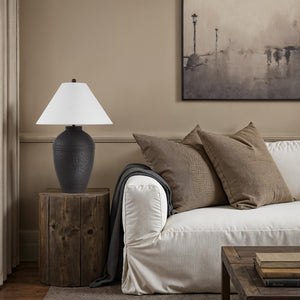 Cupper table lamp by Renwil on a wooden side table next to a sofa, featuring a white shade.