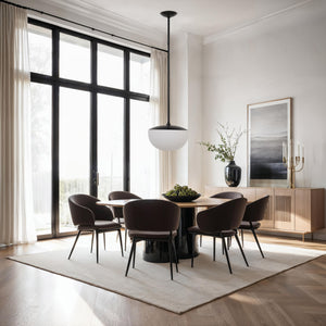 Aditi ceiling light fixture in a modern dining room, illuminating a round table surrounded by chairs.