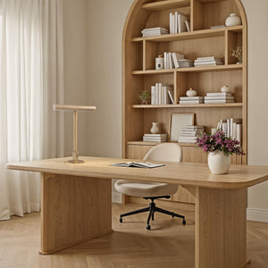 Storn Table Lamp by Renwil on a wooden desk in a cozy office with bookshelves and decor.