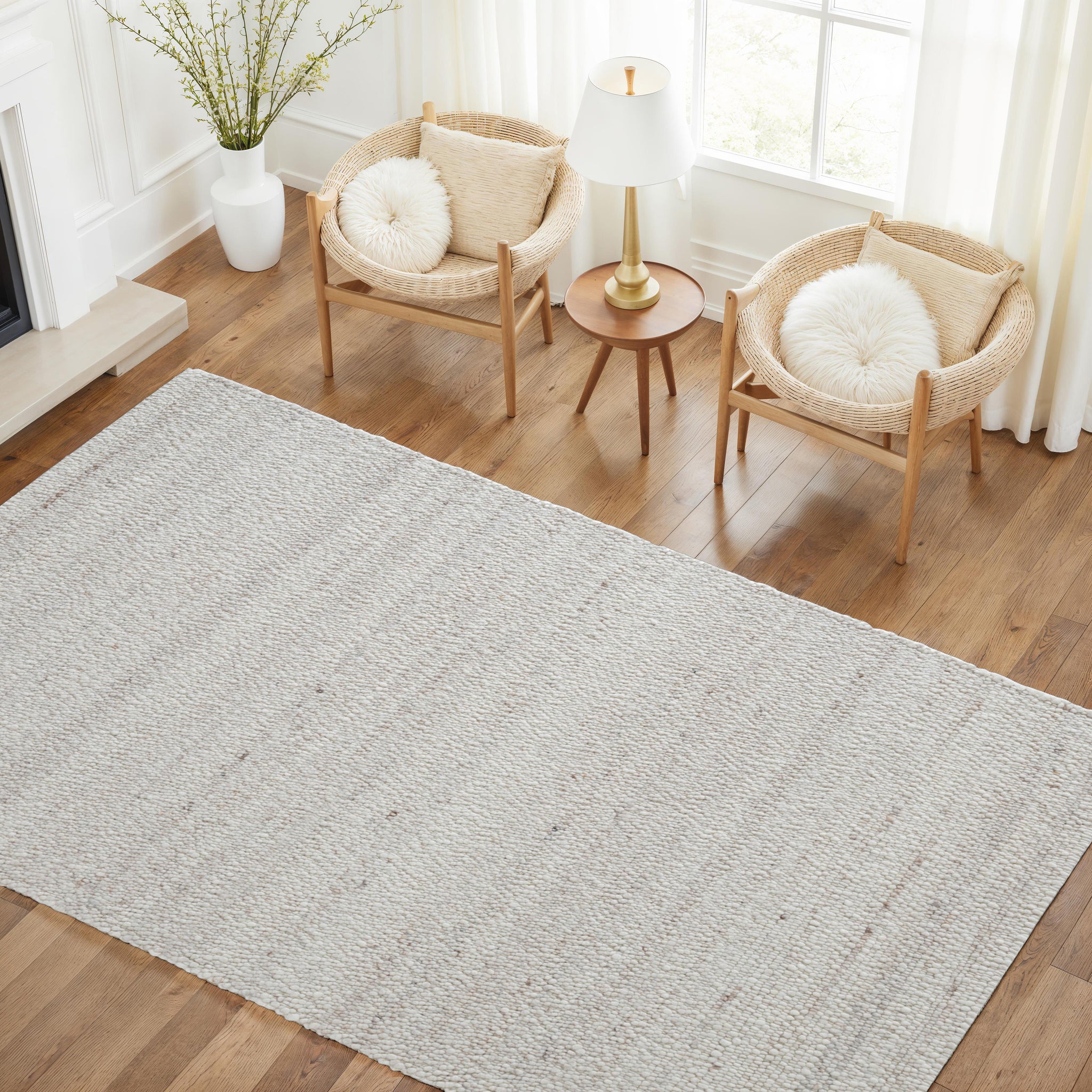 Meghan rug in light beige with textured pattern, placed on wooden floor near two chairs and a lamp.
