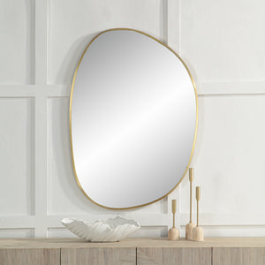 Jyn mirror with a gold frame, mounted on a white wall above a wooden console