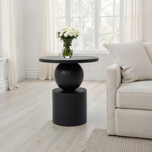 Paola side table in a bright room next to a sofa, featuring a vase of flowers.