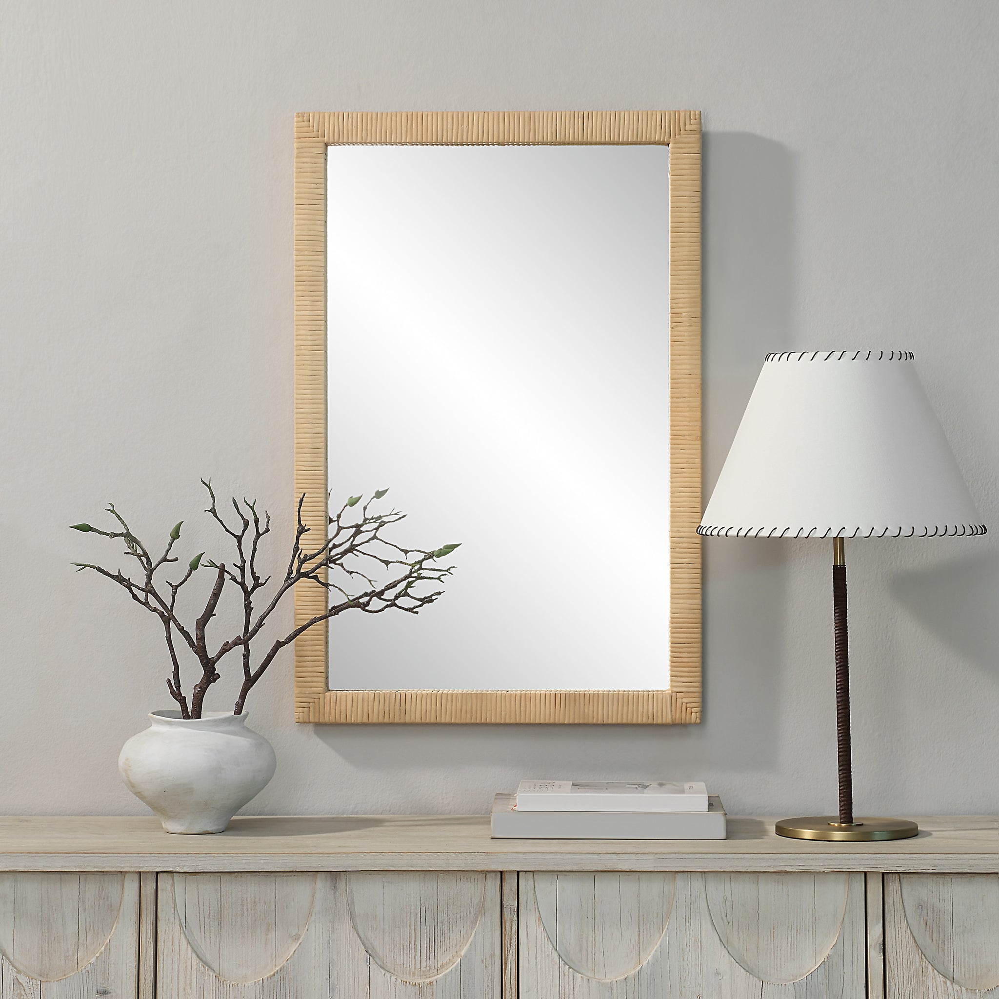 Sara mirror by Renwil displayed on a wall with a vase and lamp, featuring a natural wood frame.