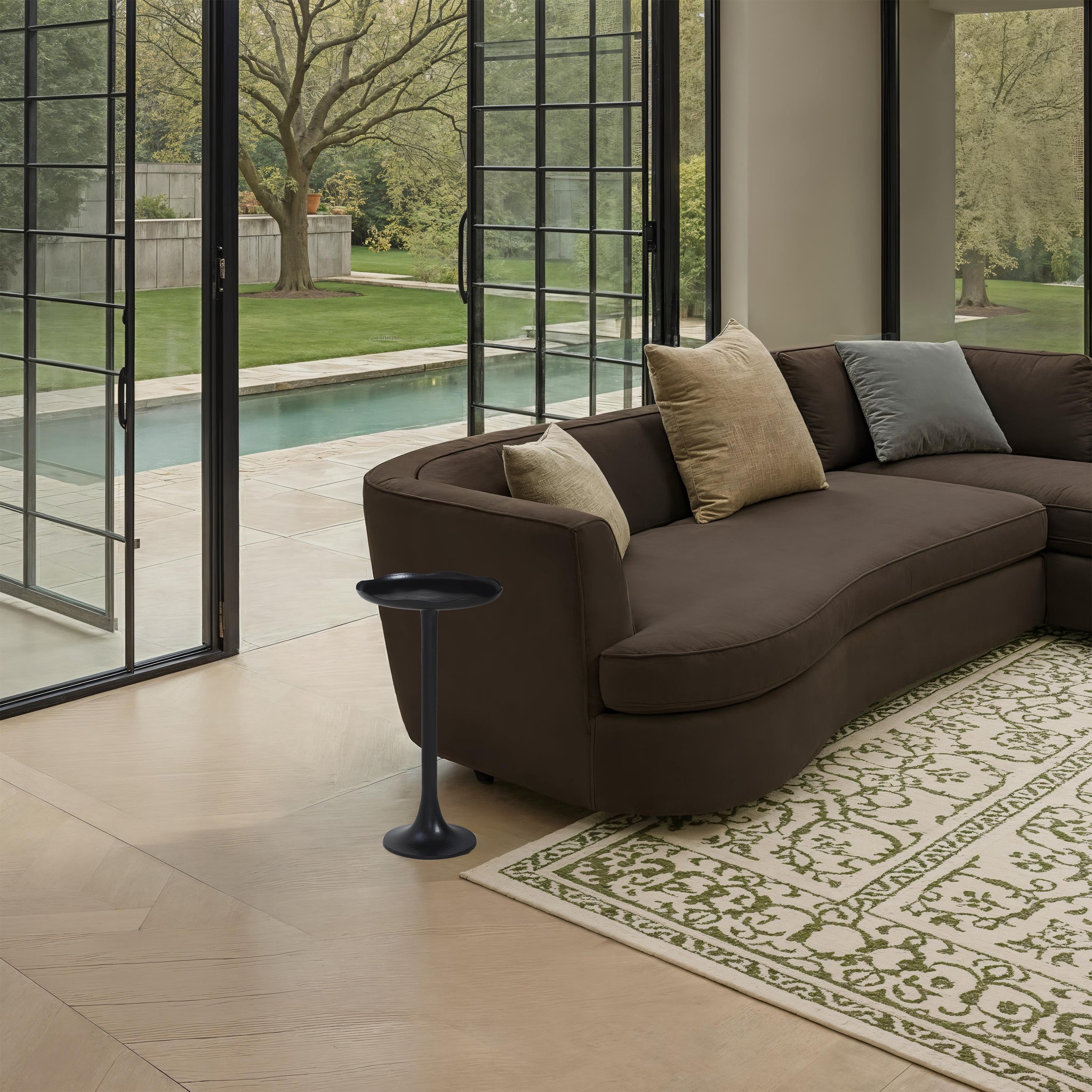Fiora side table in a modern living room setting next to a curved brown sofa.