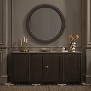Potro mirror displayed above a dark wooden cabinet with candles and flowers.