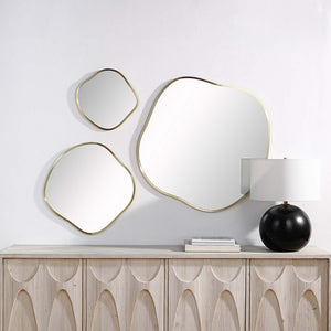 Nucleus Wall Mirrors arranged on a wall above a wooden sideboard with a lamp.