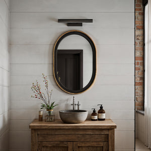 Nea wall sconce by Renwil above a modern bathroom sink with a round mirror.