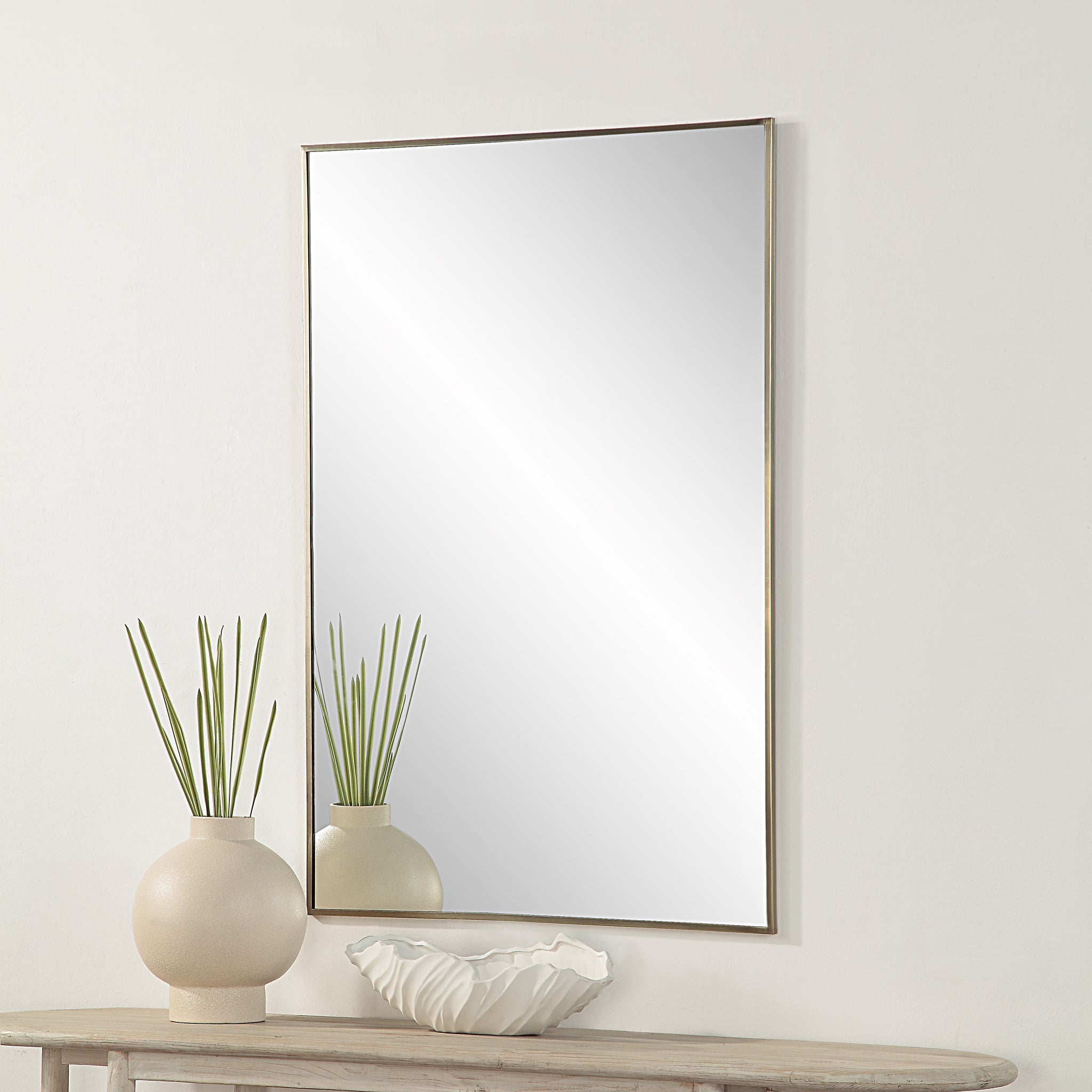 Cider Wall Mirror displayed above a table with a vase and decorative bowl, enhancing the room's decor.