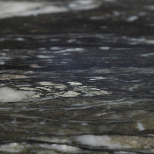 Close-up of a textured surface, resembling dark marble with white veining