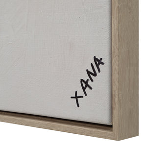 Close-up of Oriel canvas art edge showing signature 'XANA' and light wooden frame.