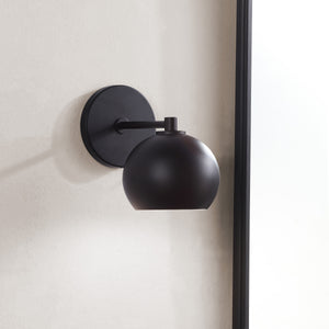 Atia Wall Sconce mounted on a wall, showcasing its round black shade