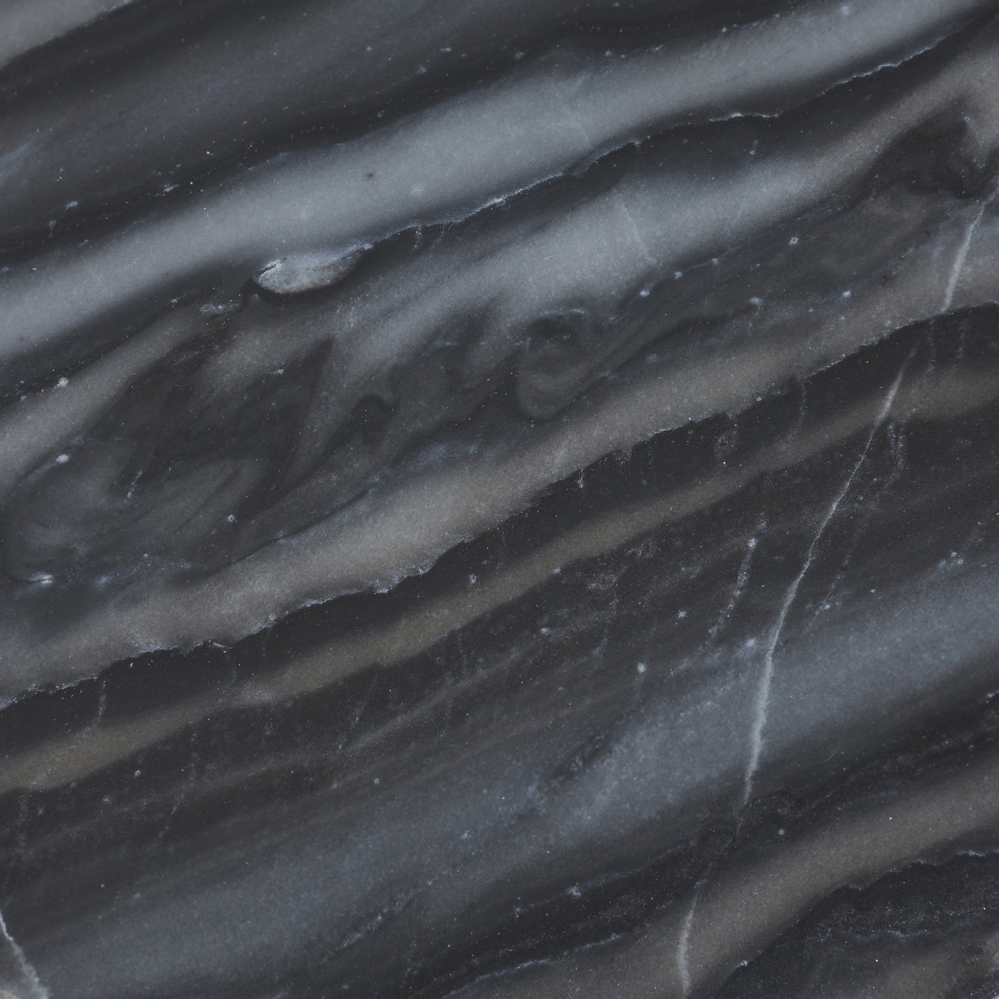 Detailed view of Mercura side table's black marble top featuring striking gray veining.