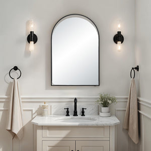 Maniola mirror mounted above a bathroom sink, complemented by stylish wall sconces.