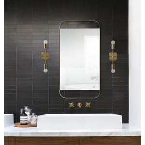 Anka Wall Sconce by Renwil in a bathroom setting, flanking a mirror on a dark tiled wall.