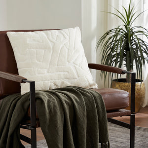 Merano indoor pillow in white displayed on a brown chair with a green throw