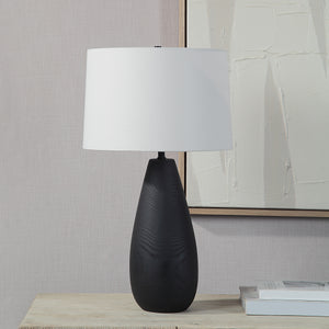 Tala Table Lamp on a table beside a modern artwork, featuring a black base and white shade