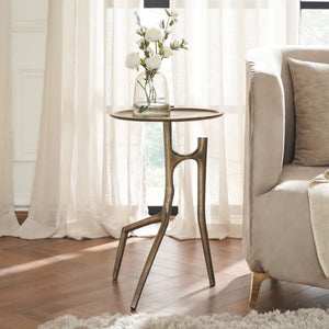 Tosca table by Renwil styled with flowers, placed next to a sofa in a bright room.