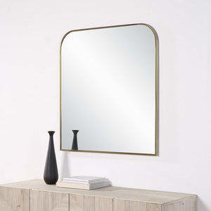 Joan Wall Mirror mounted on a wall above a wooden console with a black vase.