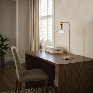 Samos table lamp on a modern desk with books and a plant, bright room ambiance.