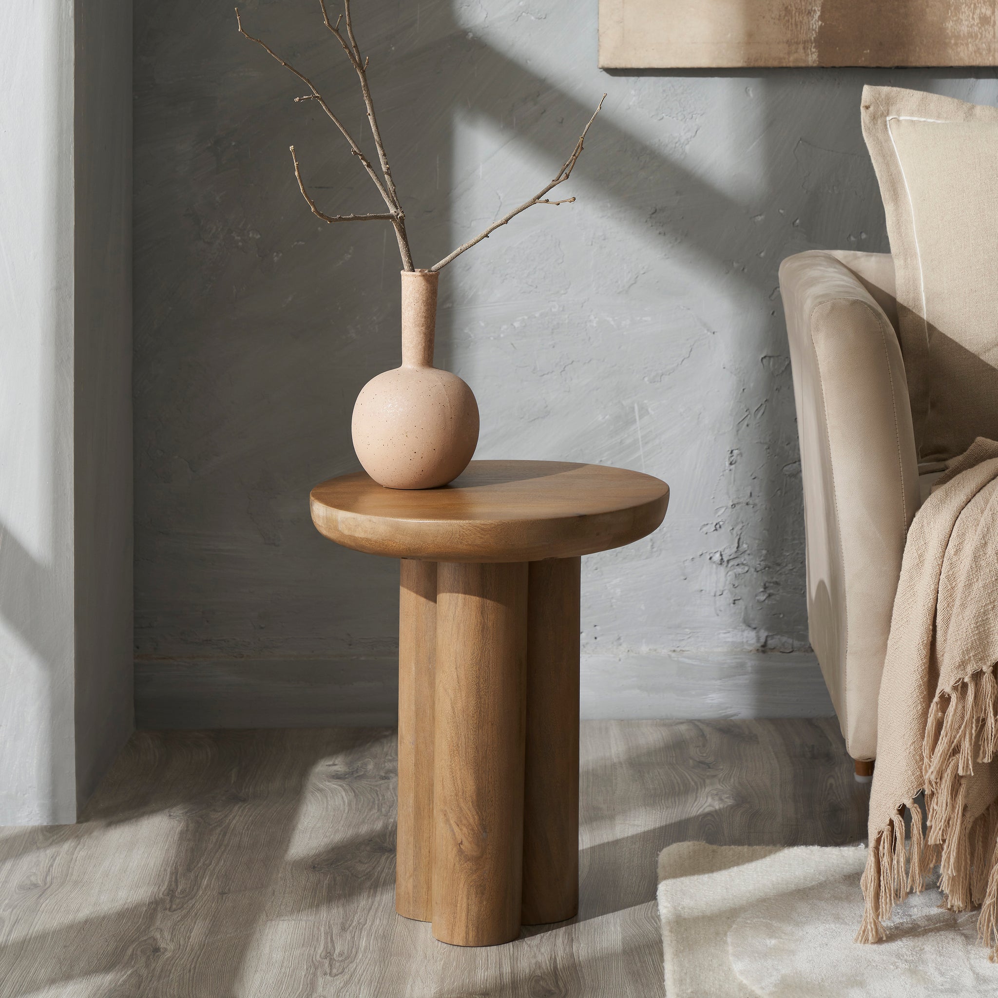 Honey Side Table styled with a vase and branches, set against a textured wall