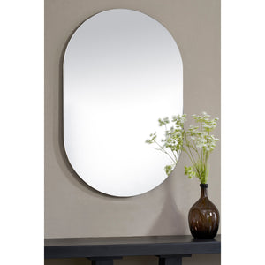 Salta mirror by Renwil, displayed on a wall with a vase of flowers in front, highlighting its oval shape.