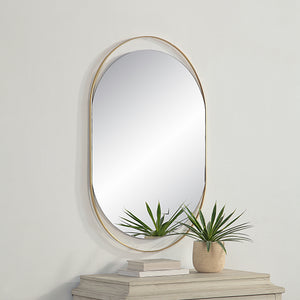 Ecru Wall Mirror mounted on a wall above a table with plants and books.