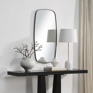 Nicoya Mirror displayed above a black console table with decorative vases and a lamp.