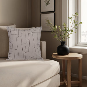 Sarno pillow on a cozy couch beside a round wooden table and a black vase.