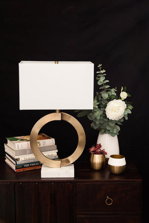 Skylar Table Lamp on a wooden table with books and decorative flowers.