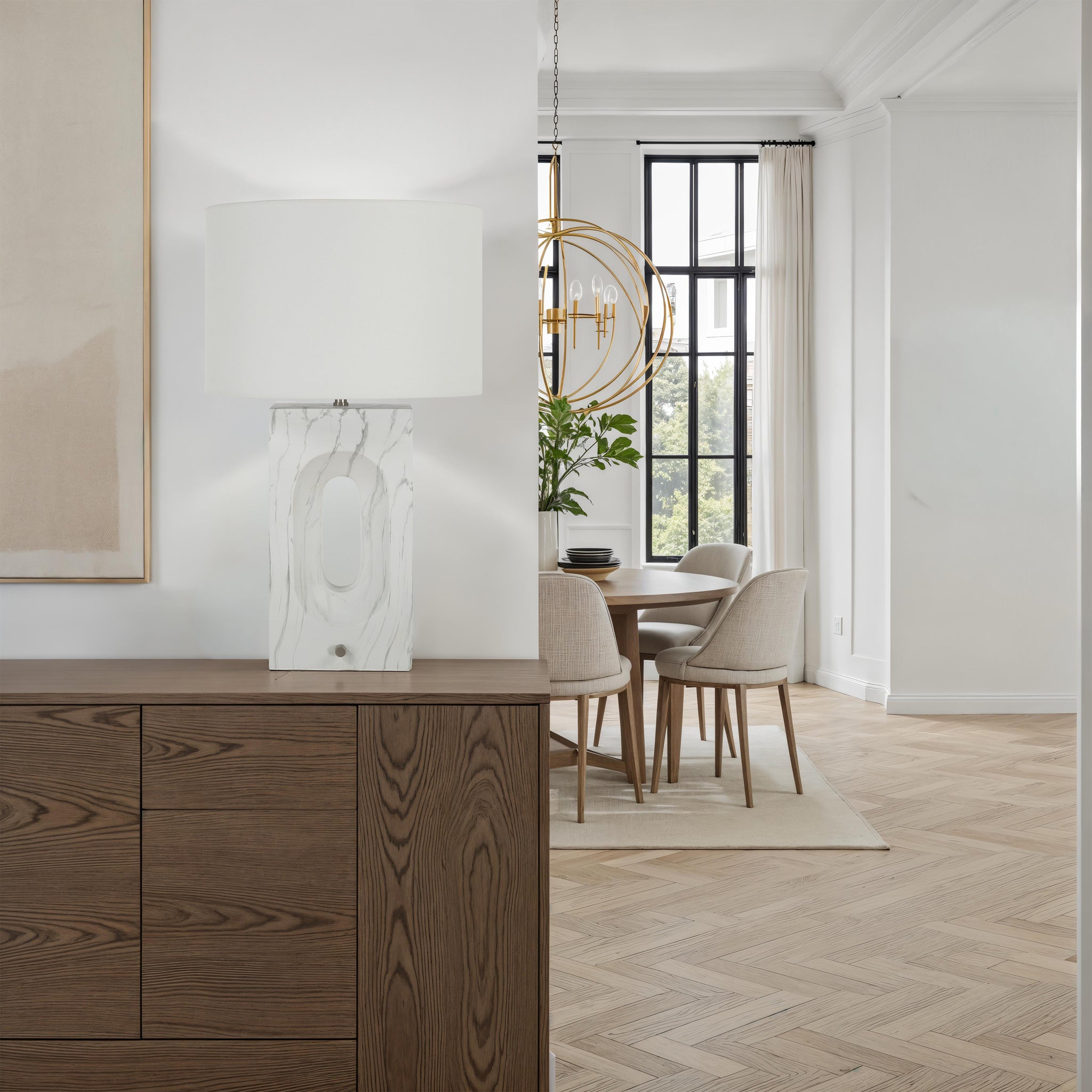 Scriba table lamp on a wooden sideboard in a bright living space with dining area.