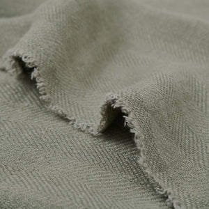 Pisces indoor pillow fabric in light green, featuring a close-up of the frayed edge and textured weave.