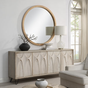 Rita mirror above a wooden sideboard, complemented by decor items and a lamp in a stylish interior.