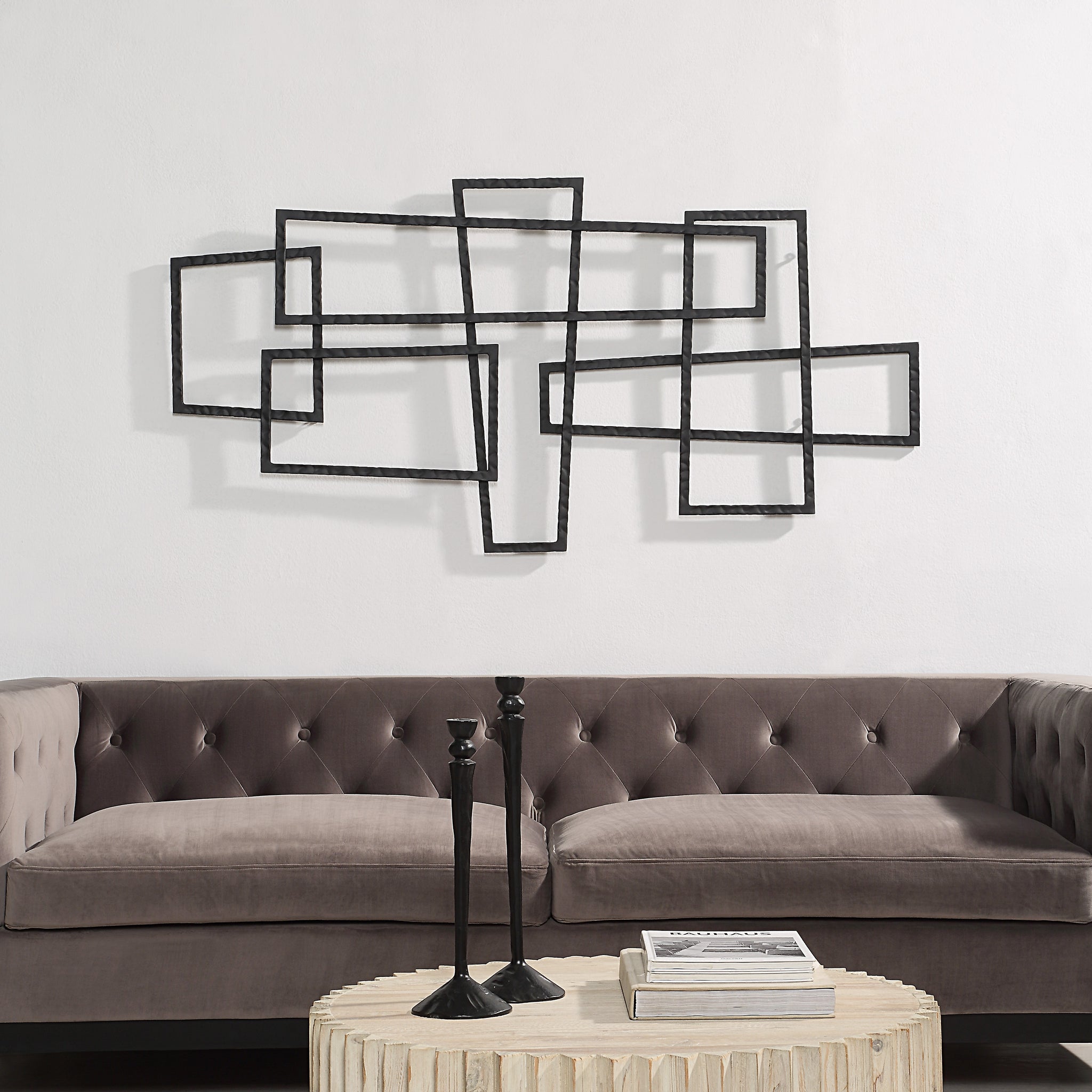 Bodkin Wall Decor mounted above a tufted gray sofa in a stylish living room setting.