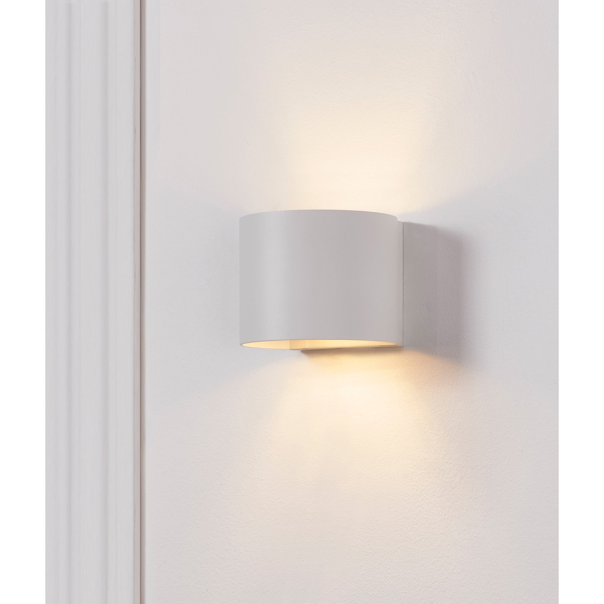 Zak Wall Sconce by Renwil, white finish on wall, illuminating with light above and below.