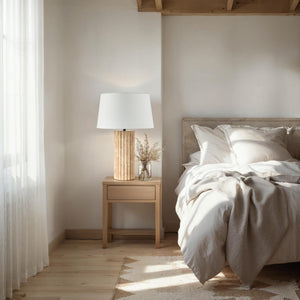 Milena Table Lamp on a nightstand beside a bed with neutral bedding