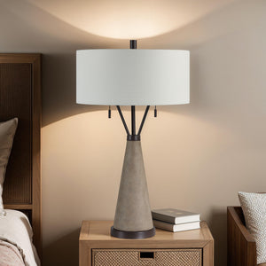 Lourdes Table Lamp on a nightstand, casting light against a wall.